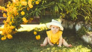 bambina in giardino sotto un cespuglio