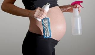 donna in gravidanza con detergenti per pulire la casa