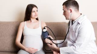medico misura la pressione a donna con pre-eclampsia