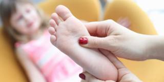bambina con piedi piatti massaggiati dalla mamma
