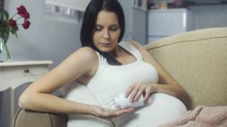 donna in gravidanza prende una pastiglia di paracetamolo