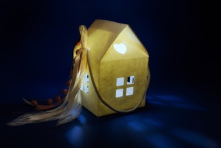 House shaped, wedding or baptism bomboniere favors isolated on dark blue and black background, inside illuminated. Copy space for text House shaped, wedding or baptism bomboniere favors isolated on dark blue and black background, inside illuminated. Copy space for text