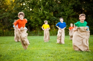 Happy Kids Having Potato Sack Race Outside