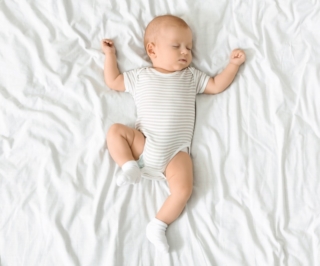 neonato che dorme con braccia alzate